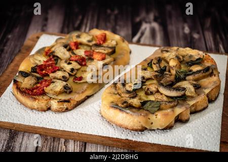 Bruschette grandi con formaggio, funghi, prosciutto e pomodoro in diverse combinazioni. Concetto di cucina mediterranea. Foto Stock