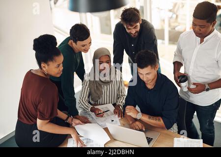 Thats impressionante. Un'immagine ritagliata di un gruppo di giovani colleghi si sono riuniti intorno a un notebook nel loro ufficio. Foto Stock