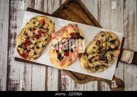 Bruschette grandi con formaggio, funghi, prosciutto e pomodoro in diverse combinazioni. Cucina mediterranea. Vista dall'alto Foto Stock