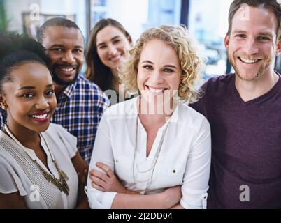 Lavoriamo per il successo piuttosto che sognare. Ritratto di un team di progettisti che si trovano in ufficio. Foto Stock