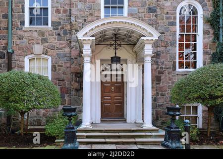 Antica casa in pietra con ingresso portico ed elegante porta frontale in legno Foto Stock