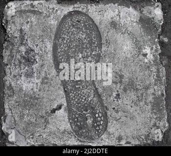 Il vecchio singolo impronta, footprint di scarpa o stivale su cemento con spazio copia, in bianco e nero Foto Stock