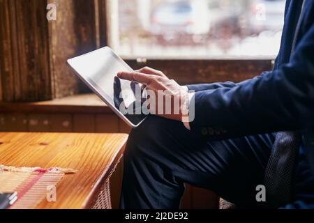 Fare una pausa dall'ufficio. Scatto corto di un uomo maturo ben vestito utilizzando un tablet digitale in un bar dopo il lavoro. Foto Stock