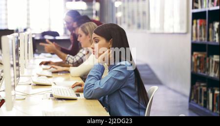 Studiare per le finali. Scatto ritagliato degli studenti universitari che studiano utilizzando i computer della biblioteca del campus. Foto Stock
