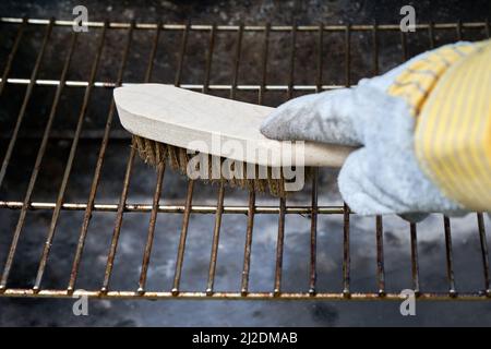 La spazzola in filo di legno pulisce la ruggine sporca della griglia del  barbecue. Guanti di protezione in pelle Foto stock - Alamy