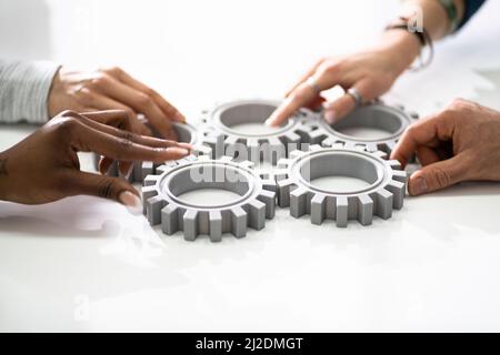 Un gruppo di imprenditori di unire insieme ingranaggi sul tavolo al posto di lavoro Foto Stock