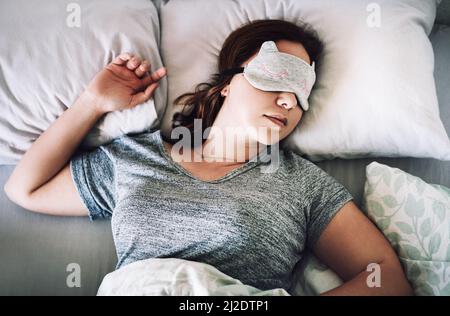 Mi meriti un sonno tranquillo. Scatto ad angolo alto di una giovane donna attraente che dorme con una maschera sul suo viso nella sua camera da letto a casa. Foto Stock