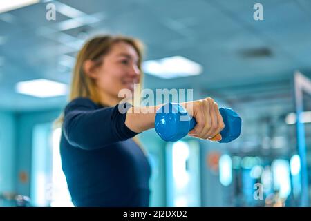 ragazza con manubri è impegnata in palestra Foto Stock