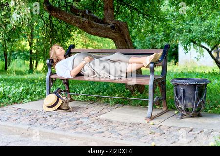 Donna incinta sdraiata su una panca del parco. Foto di alta qualità Foto Stock