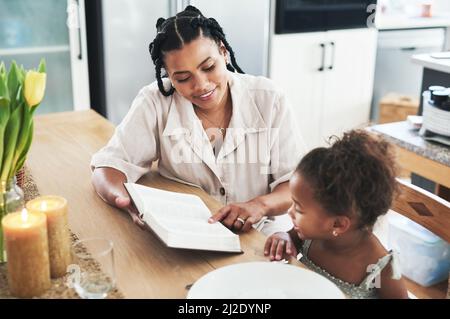 Non sono un insegnante, ma un risveglio. Shot di una madre che insegna a sua figlia la bibbia a casa. Foto Stock