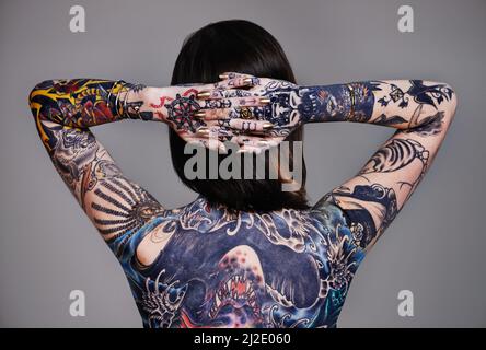 Dipinta alla perfezione. Un taglio corto di una giovane donna tatuata. Foto Stock