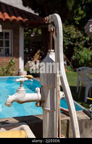vecchia pompa dell'acqua a mano con rubinetto nel giardino Foto Stock