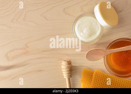 Crema idratante per la cura della pelle con estratti di miele e nido d'ape su tavola di legno. Composizione orizzontale. Vista dall'alto. Foto Stock