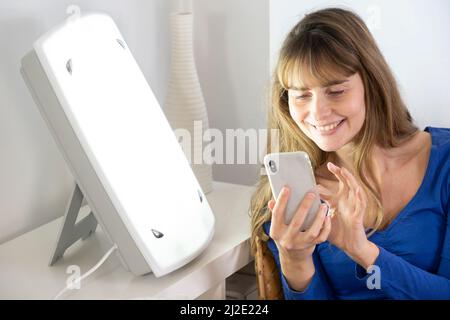 Donna smartphone terapia della luce Foto Stock