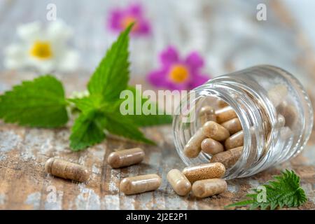 Bottiglia di pillole alimenti suplements medicina sana farmaco cura della salute trattamento additivi farmacia con piante fresche medicinali e sfondo flowerson Foto Stock