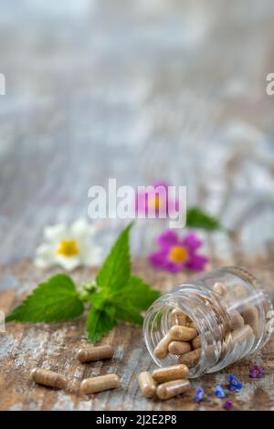 Bottiglia di pillole alimenti suplements medicina sana farmaco cura della salute trattamento additivi farmacia con piante fresche medicinali e sfondo flowerson Foto Stock