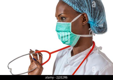 Dottore africano americano femminile, infermiere donna che indossa un cappotto medico, cappuccio, con stetoscopio e maschera. Foto Stock