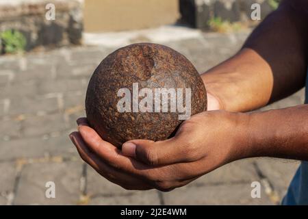 Uomo che tiene la palla di cannone in mano, forte Korigad, Pune, Maharashtra, India Foto Stock