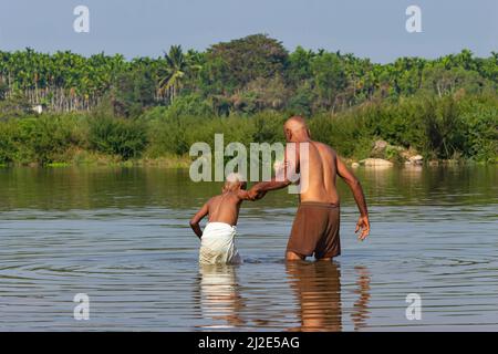 INDIA, KARNATAKA, SHIVAMOGA, febbraio 2022, uomo che tuffa Boy nel fiume per il rituale indù, Kudli Foto Stock
