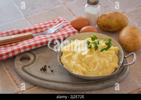 purea di patate in un piatto con patate, latte, uova su un tavolo Foto Stock