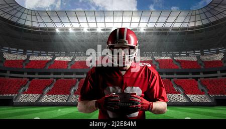 Immagine composita del giocatore di rugby maschile caucasico che tiene una palla di rugby contro lo stadio sportivo Foto Stock