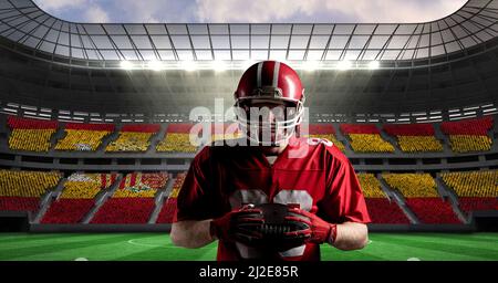 Immagine composita del giocatore di rugby maschile caucasico che tiene una palla di rugby contro lo stadio sportivo Foto Stock