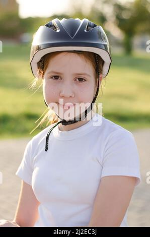 Ritratto di una ragazza di 11 anni dai capelli rossi in un casco per bicicletta. Ragazza atleta in un casco protettivo sulla testa Foto Stock