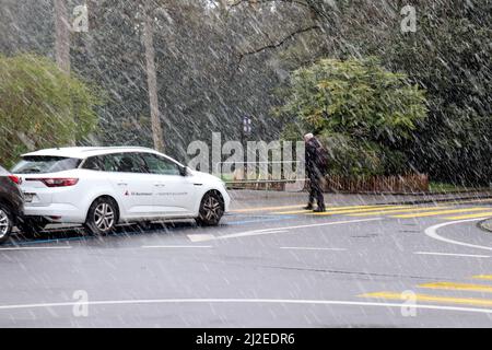 Ginevra, Svizzera, 2022-04-01 l'uomo attraversa la strada attraverso la neve. Il primo giorno di aprile è iniziato con il tempo del vino. Credit: marcio cimatti/Alamy Live News Foto Stock