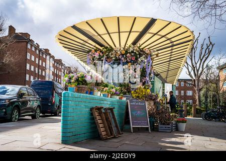 Londra, UK - 12 marzo 2022: Wild at Heart flower stall a Turquoise Island, Notting Hill. Questo edificio iconico e' uno dei pochi servizi igienici pubblici elencati Foto Stock