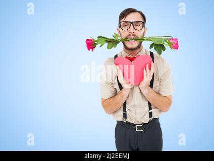 Uomo caucasico con rose in bocca che tiene un cuore rosso contro lo spazio copia su sfondo blu Foto Stock