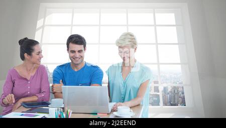 Immagine composita di un gruppo di persone che utilizza un computer portatile contro la vista del paesaggio urbano dalla finestra dell'ufficio Foto Stock