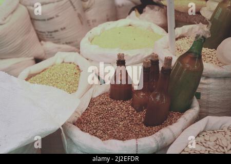 Diversi semi crudi organici in un sacco con bottiglie di vetro bloccato in uno dei sacchi per la fermentazione o solo stoccaggio. Foto Stock