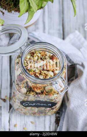 Contenitore per vasetti di vetro con coperchio superiore basculante aperto pieno di granola di cheto vegano a base di noci pecan, nocciole, cocco non zuccherato, semi di girasole, pepita Foto Stock