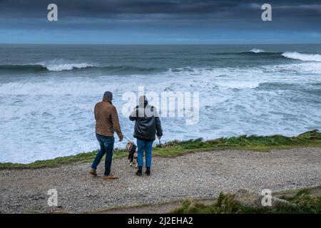 Camminatori di cani sul percorso della costa durante le condizioni meteorologiche tempestose sulla costa nord della Cornovaglia. Foto Stock