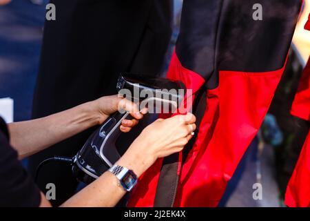 Cropped femmina vesti a vapore su appendiabiti. Donna con vaporetto pulizia abiti vista laterale, spazio copia. Signora caucasica bionda che usa il vapore elettrico del MODER Foto Stock