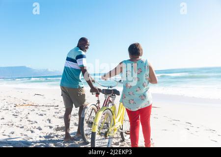 African american pensionato senior coppia con biciclette in spiaggia il giorno di sole Foto Stock