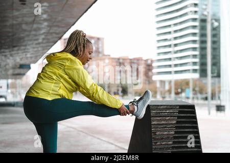 Donna africana anziana che fa esercizi di stretching all'aperto - anziani sportivi persone concetto di stile di vita Foto Stock