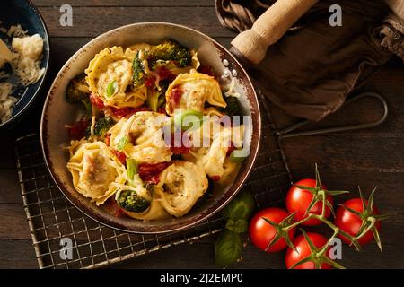 Il top shot dello studio di tortelloni appetitosi a base di pomodori, broccoli e formaggio Foto Stock