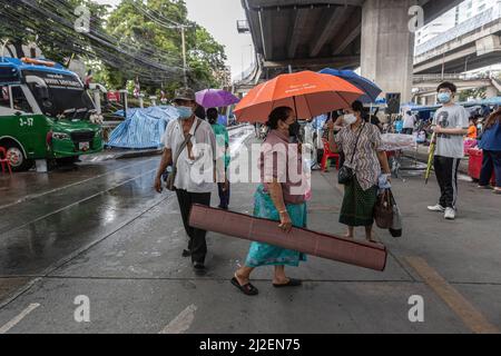 Bangkok, Tailandia. 22nd Mar 2022. Una donna porta la sua stuoia per dormire in una zona asciutta mentre inizia a piovere durante la protesta degli agricoltori. Gli agricoltori provenienti da tutta la Thailandia si sono accampati fuori dal Ministero delle Finanze a Bangkok per due mesi. Essi hanno chiesto il sostegno del governo per la ristrutturazione del loro debito e per il miglioramento della loro situazione finanziaria, mentre il prezzo di mercato del riso è diminuito costantemente negli ultimi anni, il prezzo dei fertilizzanti e del carburante continua ad aumentare, costringendo molti agricoltori a prendere prestiti che poi lottano per ripagare. Credit: SOPA Images Limited/Alamy Live News Foto Stock