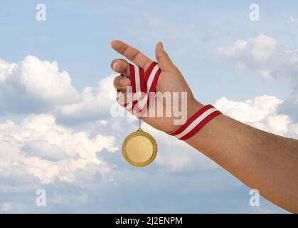 Uomo che alza la mano e tiene medaglia d'oro. Concetto di ambizione perseveranza e vittoria. Foto Stock