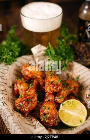 Porzione di bastoncini di pollo fritti in profondità e ricoperti di salsa calda (condita con). Servito con una metà di lime su carta artigianale. Foto Stock