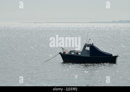 Una piccola barca a motore ancorata mentre la marea arriva a Leigh-on-Sea, Inghilterra, in una giornata di nebbia. Foto Stock