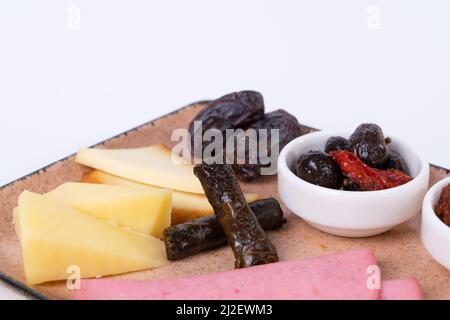 Vista ravvicinata di noci, olive, concentrato di pomodoro, fette di formaggio, impacco, prosciutto, albicocche secche, dattero e formaggio cheddar su fondo bianco isolato, oppos Foto Stock