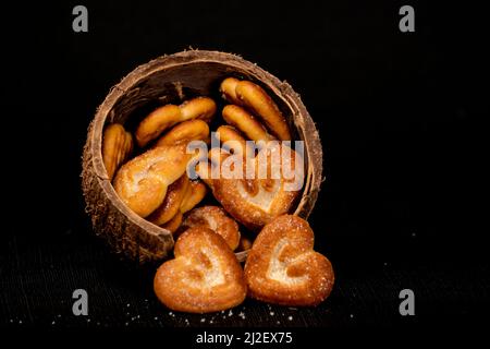 Molto primo piano, biscotti a forma di cuore in conchiglia di cocco, isolato con sfondo nero Foto Stock