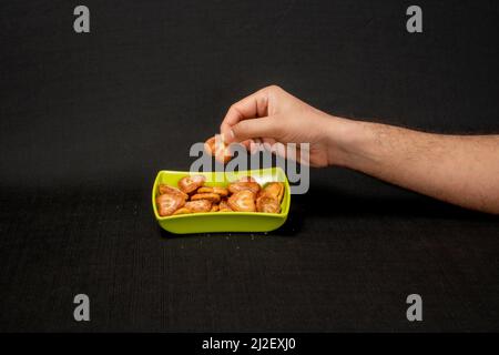 Cuori a forma di biscotto in Green Square Bowl, Boy Hand Pickup the Biscuit, isolato su sfondo nero Foto Stock