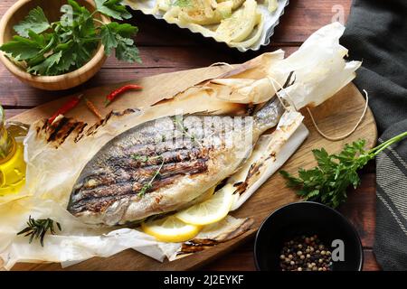 Concetto di cucina. Delizioso pesce al forno con erbe aromatiche, spezie e limone. Orata di mare. Cibo sano, dieta. Direttamente sopra. Foto Stock