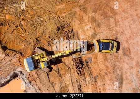 Il convogliatore dell'escavatore carica un terreno nel dumper di scarico durante la preparazione del luogo al cantiere per la casa di complessi residenziali Foto Stock