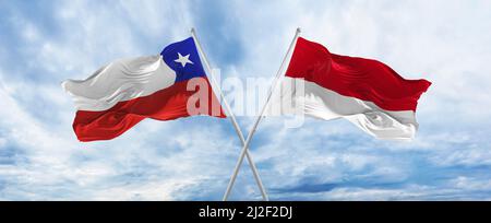 Bandiere nazionali incrociate del Cile e della bandiera del Principato di Monaco che sventolano nel vento al cielo nuvoloso. Simboleggiare il rapporto, il dialogo, il viaggio tra due paesi. Copia Foto Stock