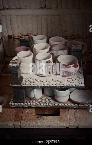 tazze di argilla in forno per la cottura di ceramica in studio di ceramica. Foto Stock