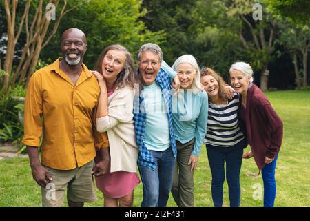 Ritratto di felice multirazziale senior maschile e femminile amici godendo in cortile Foto Stock